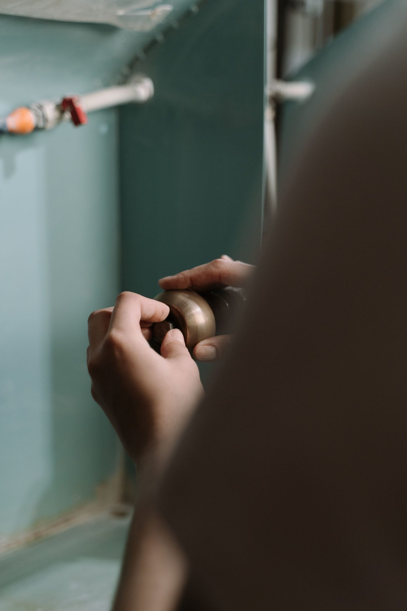 Hands tightening a pipe fitting under a kitchen sink