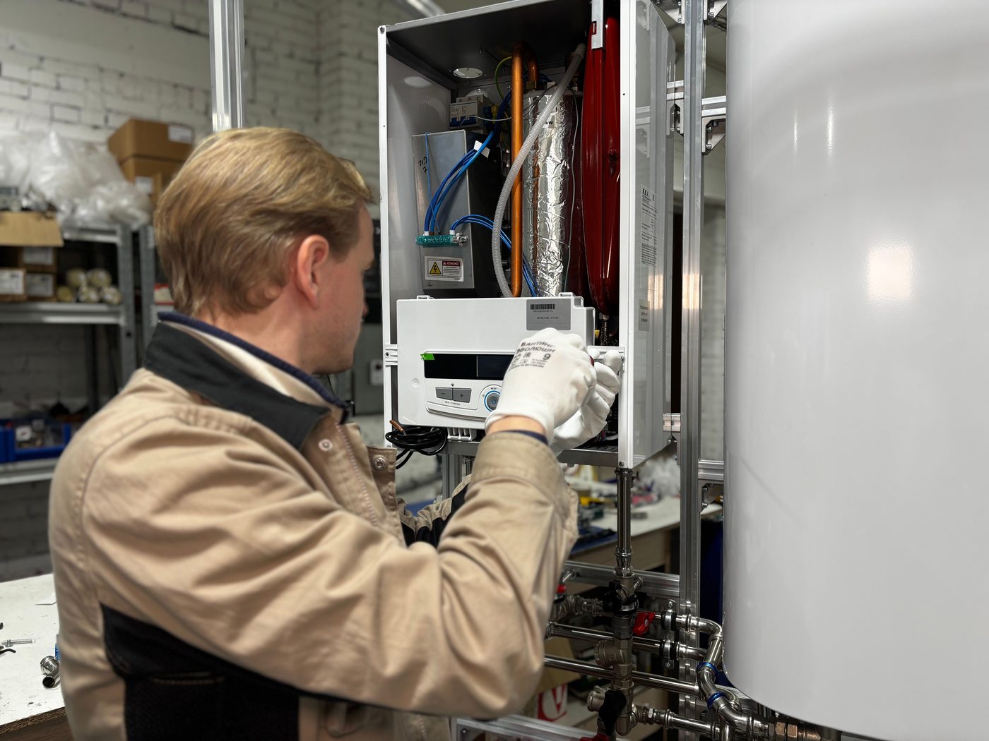 Engineer in gloves working on a wall boiler with its casing off