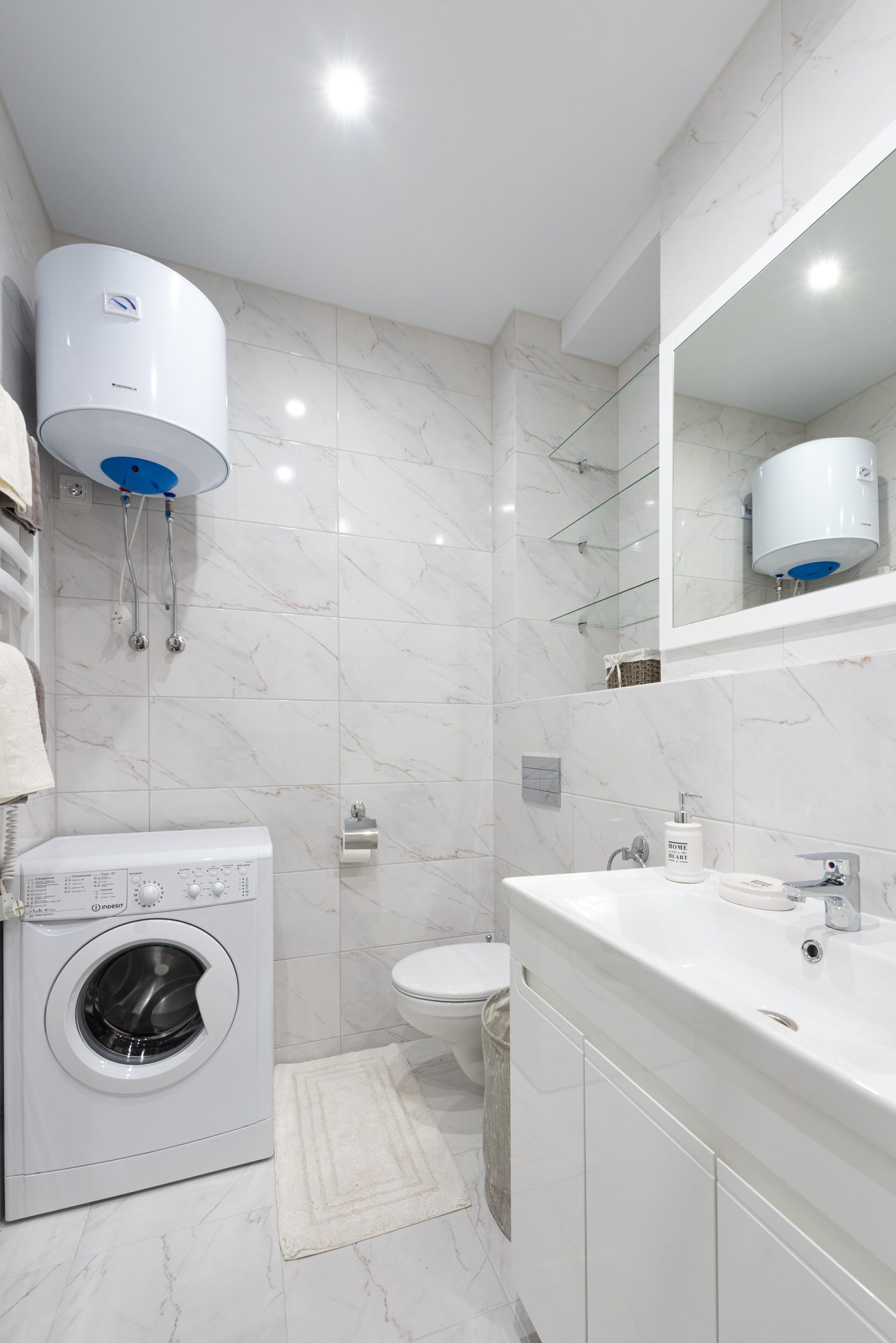 Small white bathroom with a wall-mounted water heater above a washing machine